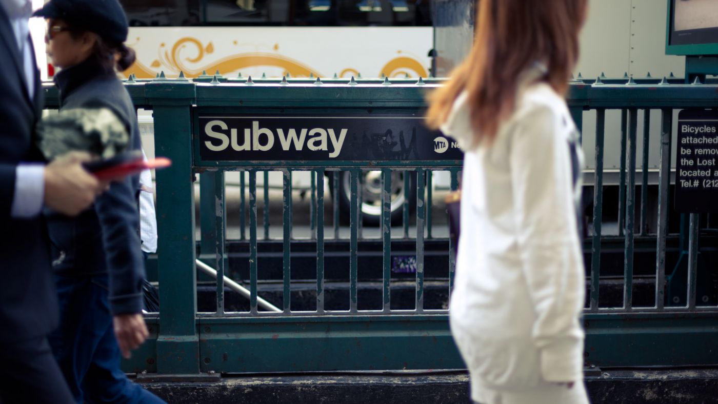 Woman walking in front of a Subway entrance, New York