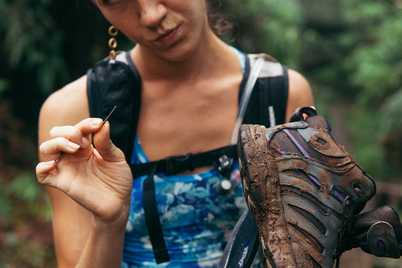 Woman pulling metal piece form shoe, Koke'e State Park, Kaua'i, Hawaii