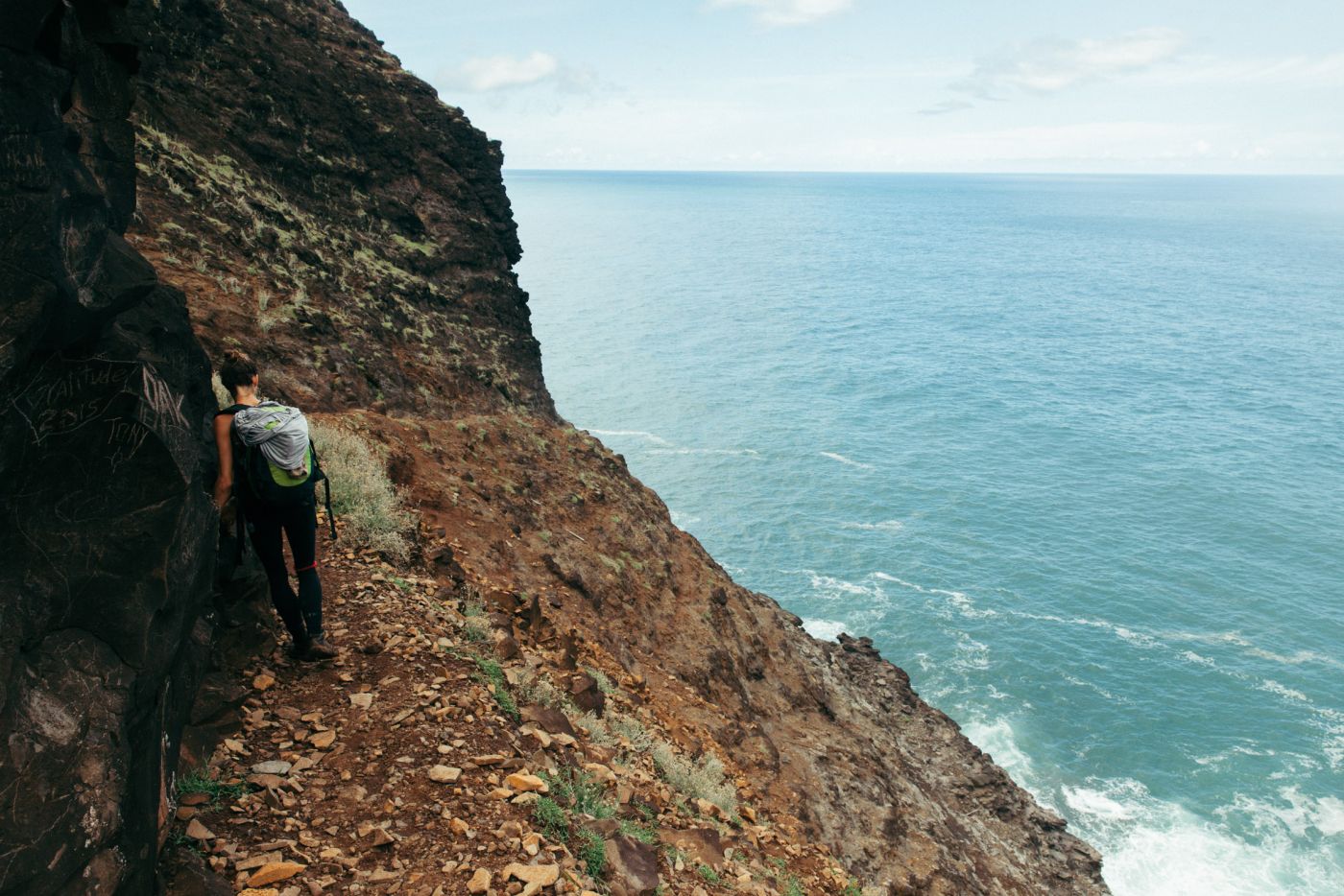 Woman hiking against a cliff, Kalalau Trail, Kaua'i, Hawaii