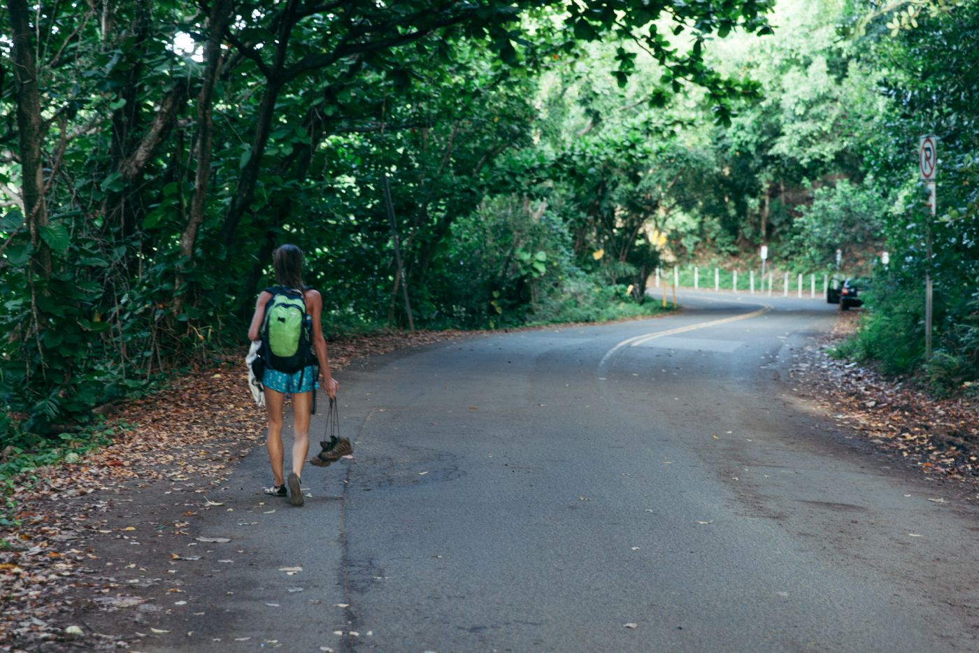 Woman walking with hiking shoes in hand, Kee Beach, Kauai, Hawaii